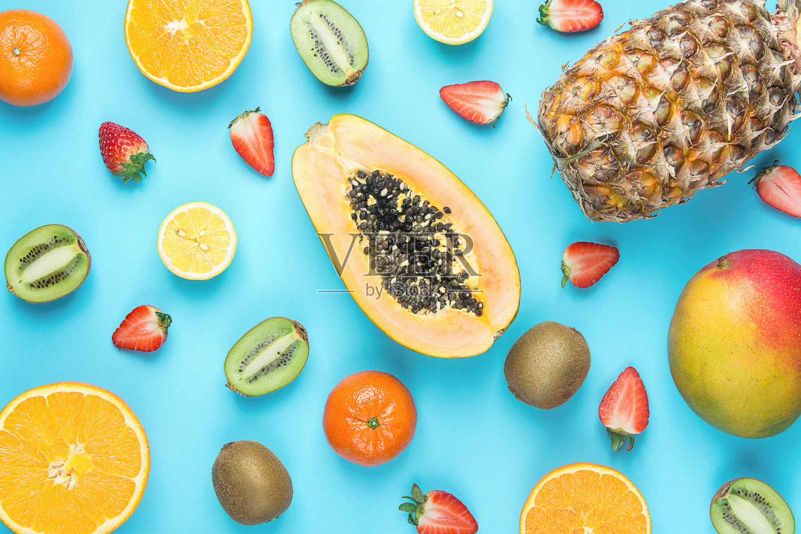 不同热带季节夏季水果品种。木瓜，芒果，橘子，柑橘，橙子，菠萝，柠檬，草莓，猕猴桃在蓝色的背景。健康生活方式饮食维生素。平躺照片摄影图片
