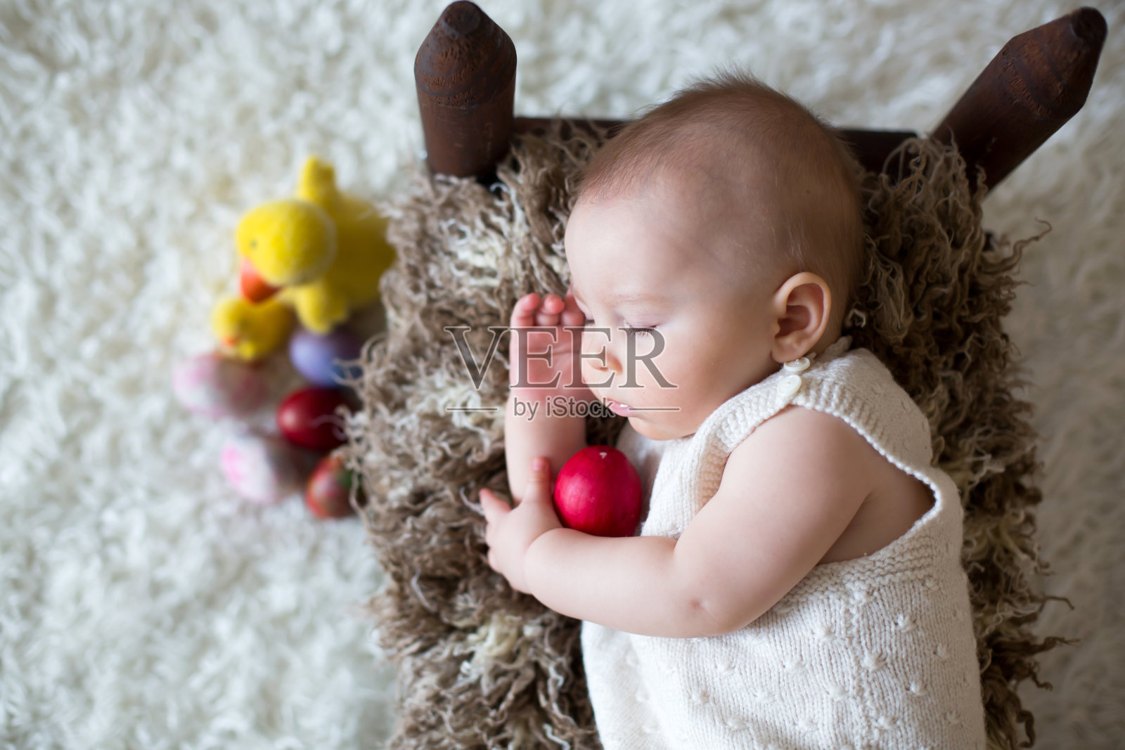 可爱的蹒跚学步的小男孩，和五颜六色的复活节彩蛋和装饰小鸭子一起睡觉照片摄影图片