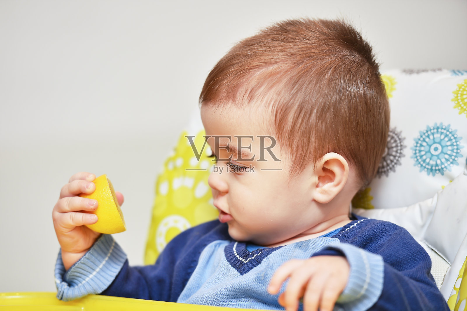 小男孩坐在婴儿椅上，还有柠檬照片摄影图片