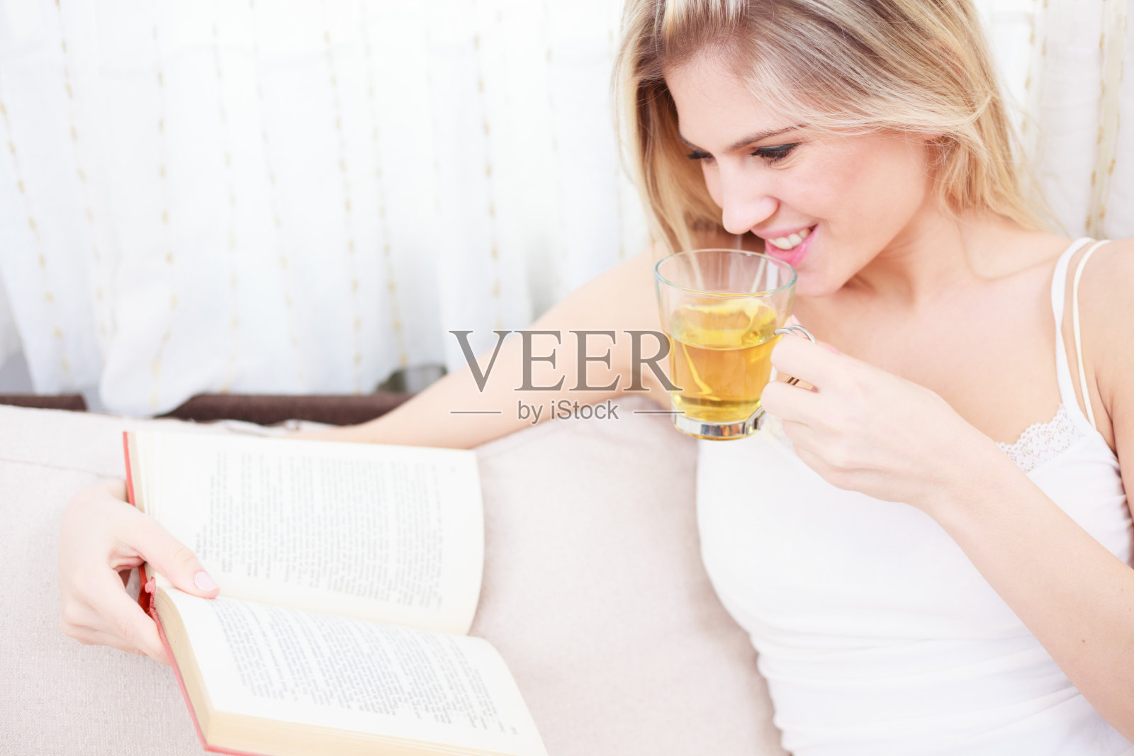 美丽的年轻女子读着一本书，拿着一杯茶照片摄影图片