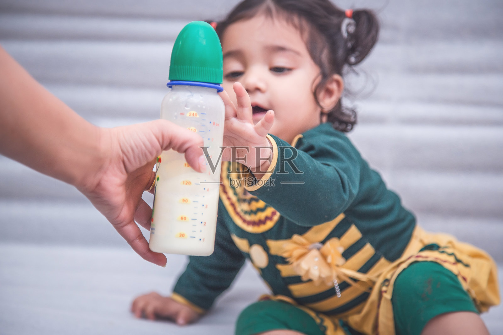 妈妈给小女孩一瓶牛奶。照片摄影图片