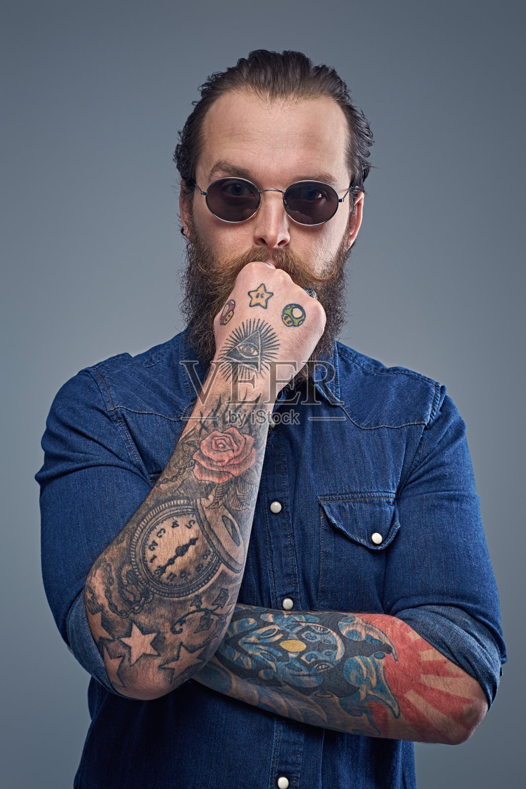 一个有思想的大胡子男人，手臂上有纹身。照片摄影图片