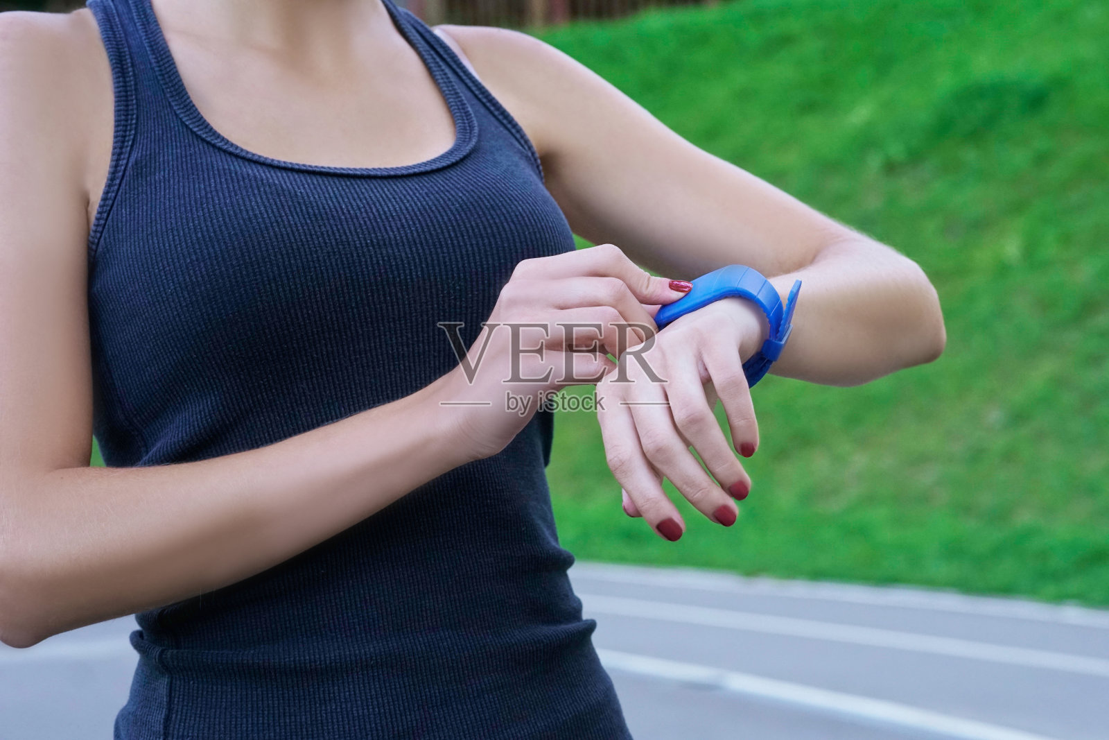近距离拍摄的年轻女子慢跑准备跑看智能手表。照片摄影图片