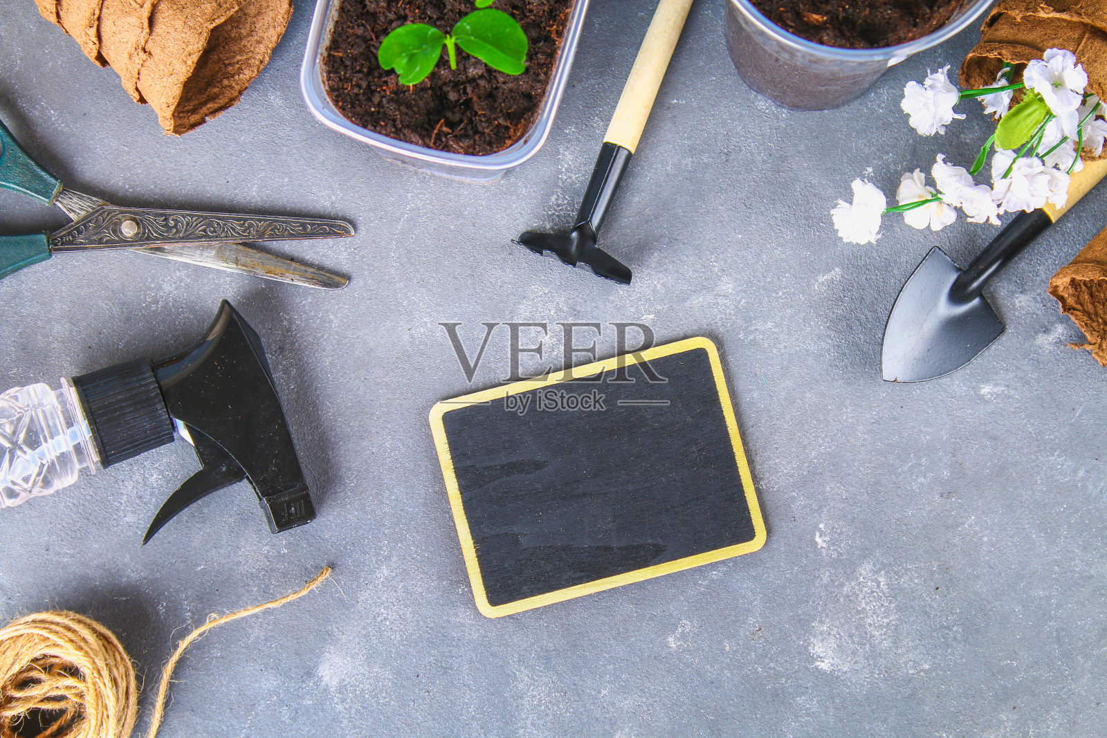 灰色混凝土背景上的园艺工具和花盆。粉笔板。俯视图，复制空间。照片摄影图片