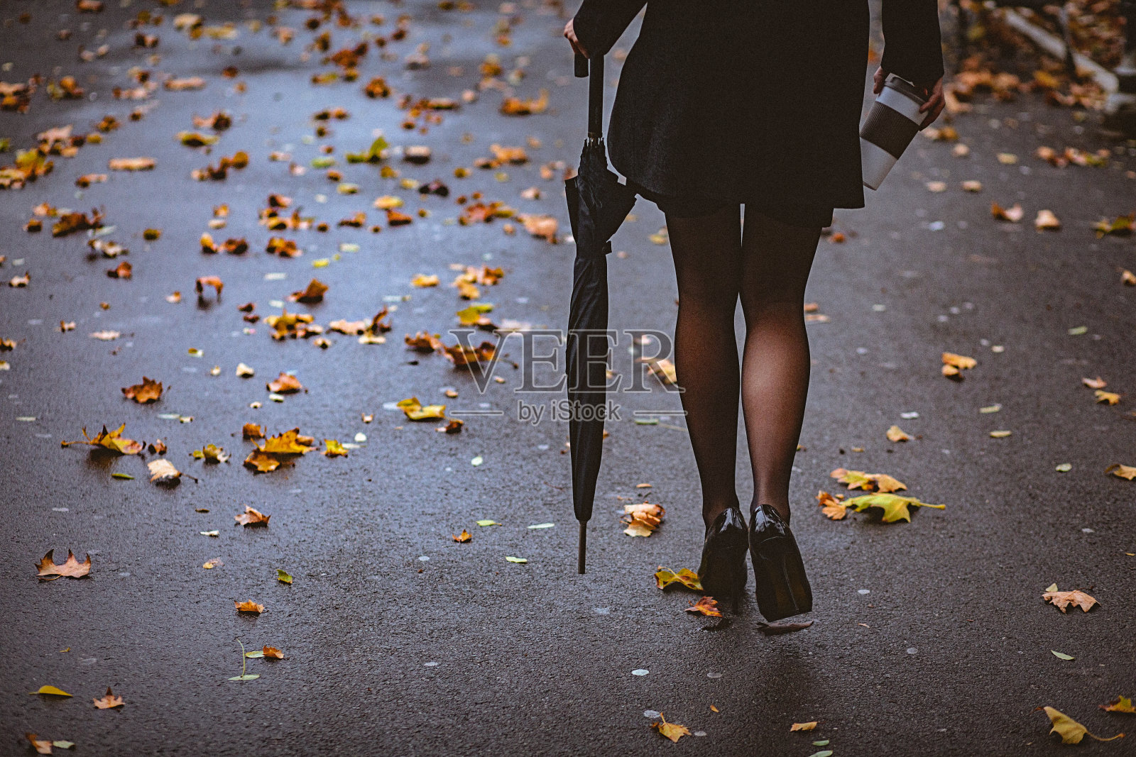 一个优雅的女人穿着高跟鞋走在潮湿的人行道上照片摄影图片