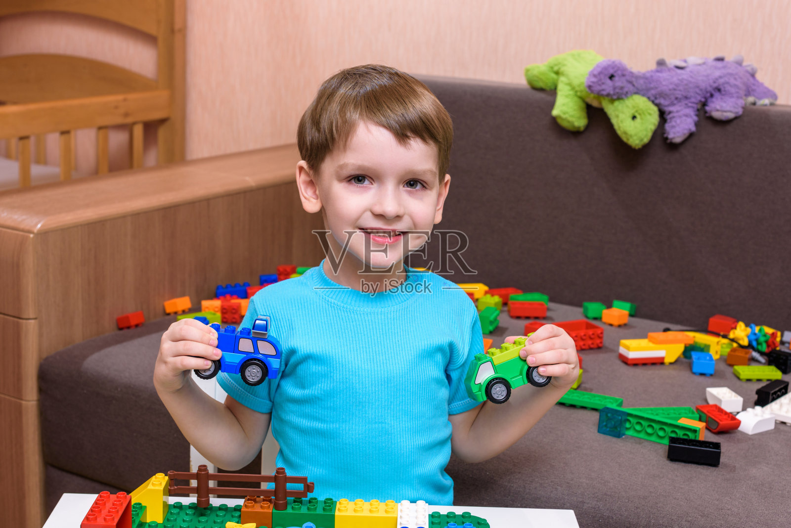 白人小孩在室内玩五颜六色的塑料积木。穿着衬衫的小男孩，玩着建筑创造照片摄影图片