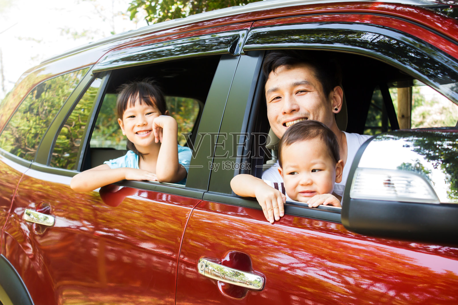 亚洲家庭微笑在红色的车，行动在车窗车。父亲和两个女儿幸福情感。照片摄影图片