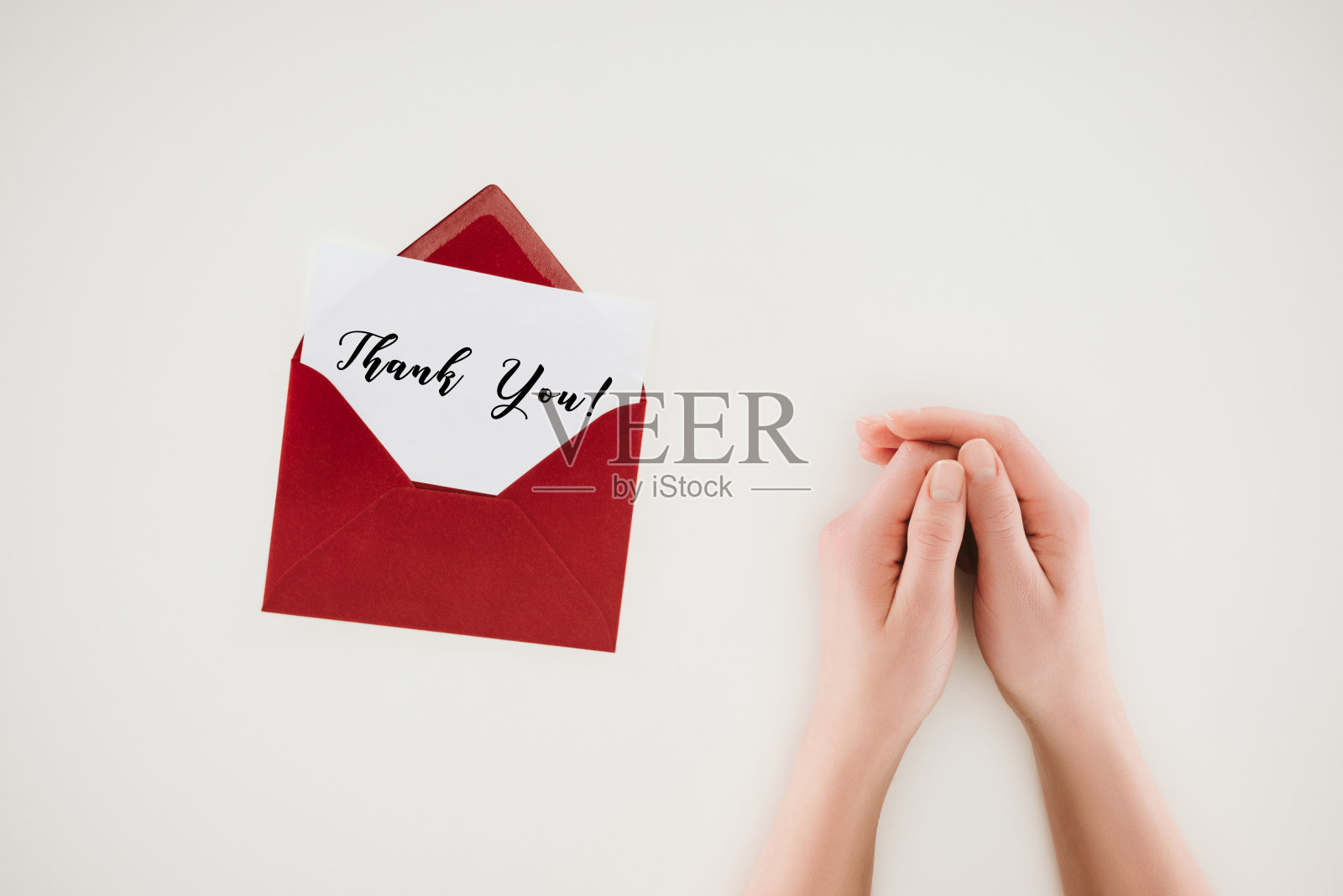 剪下的女人手附近打开了红色信封与感谢信在纸孤立的白色照片摄影图片