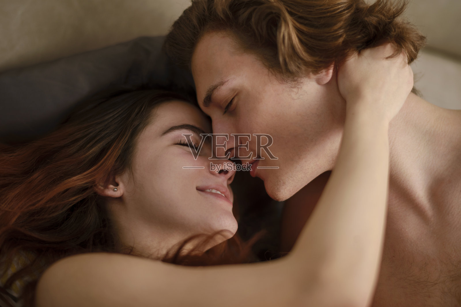 性感的年轻夫妇躺在床上的肖像照片摄影图片