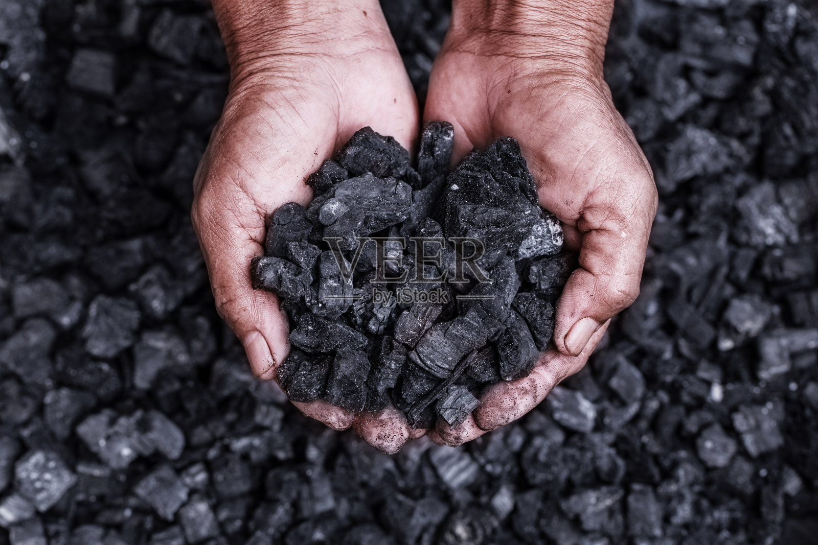 煤矿开采-煤矿工人在男人手中的煤炭背景。描绘关于煤炭开采或能源、环境保护的想法。工业煤。火山岩。照片摄影图片