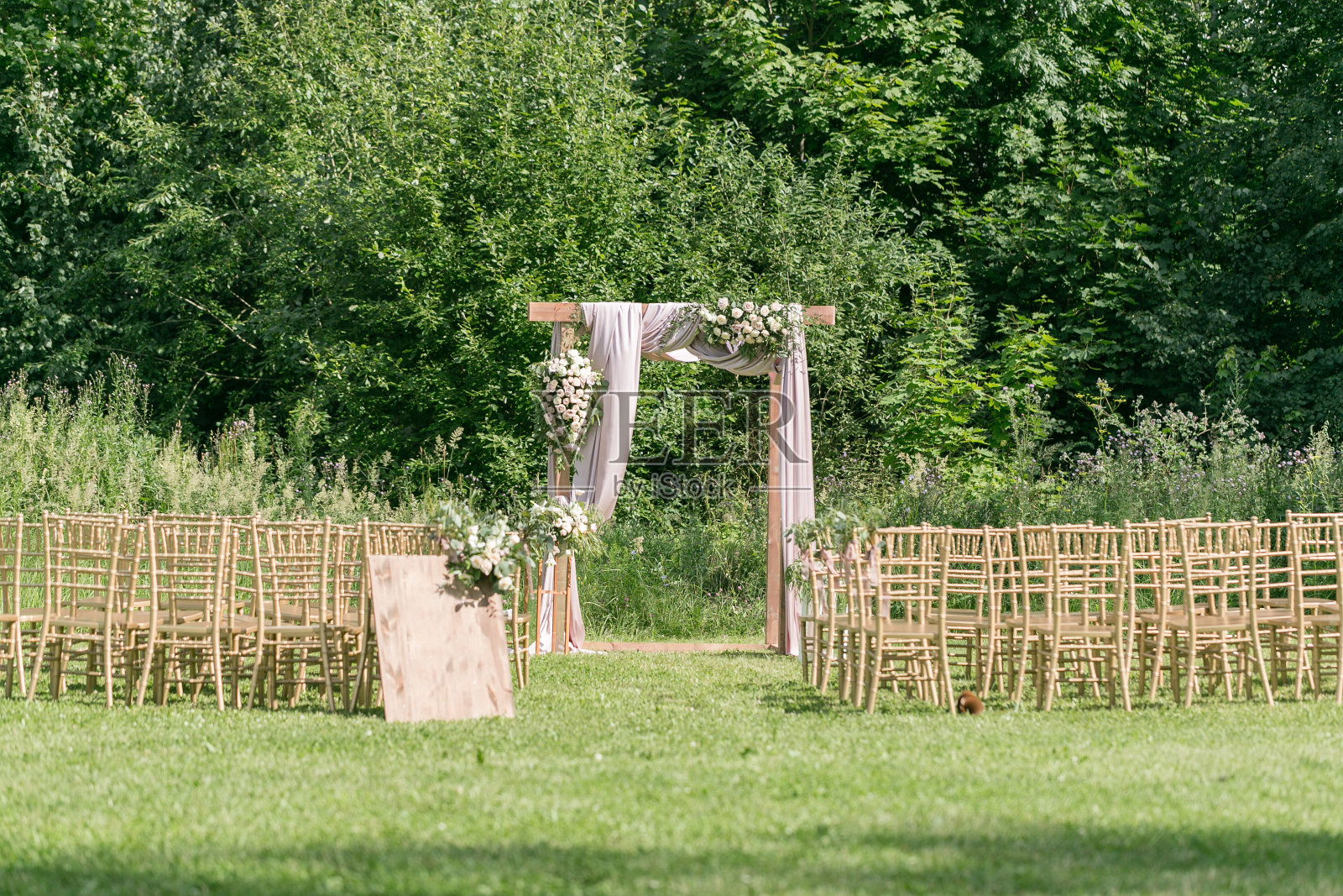 美丽的设置为户外婚礼仪式，等待新娘和新郎和客人。木椅上装饰着鲜花，都是在一片森林里举行婚礼的地方照片摄影图片