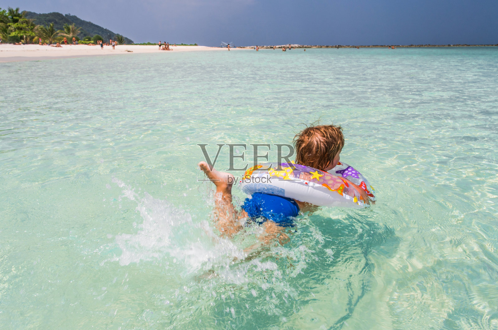 后视图的小孩游泳在大海与充气环。照片摄影图片