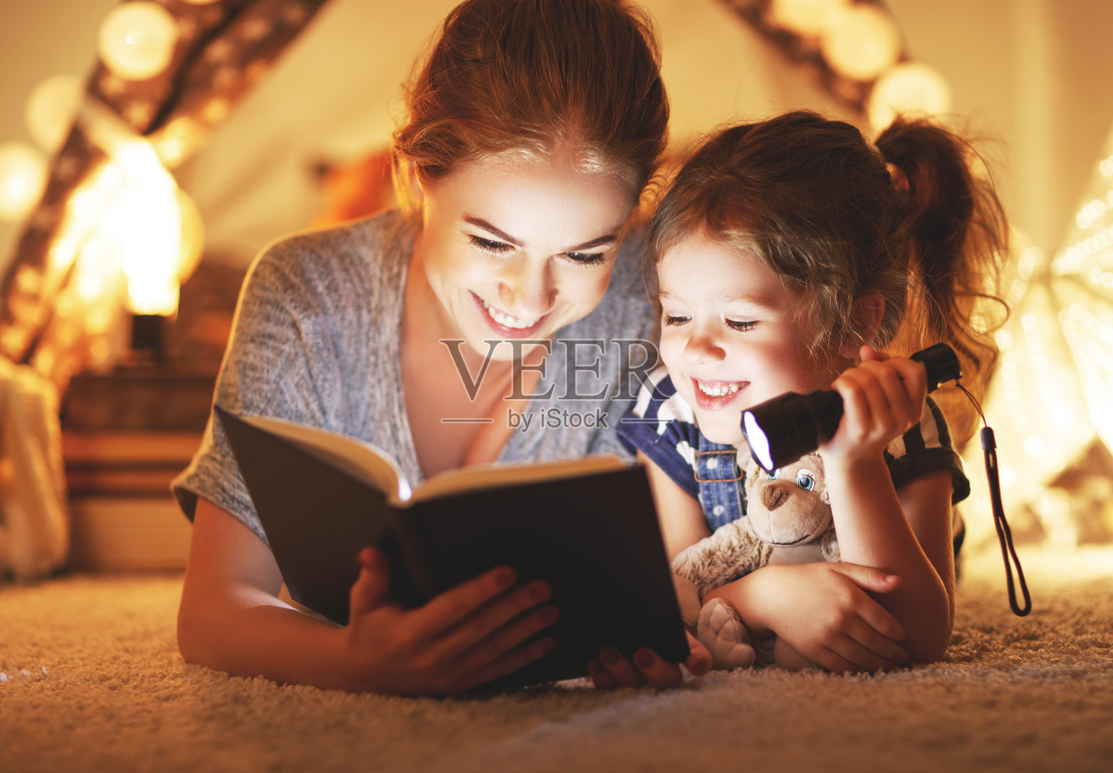 妈妈和孩子在睡觉前看一本书和一个手电筒照片摄影图片