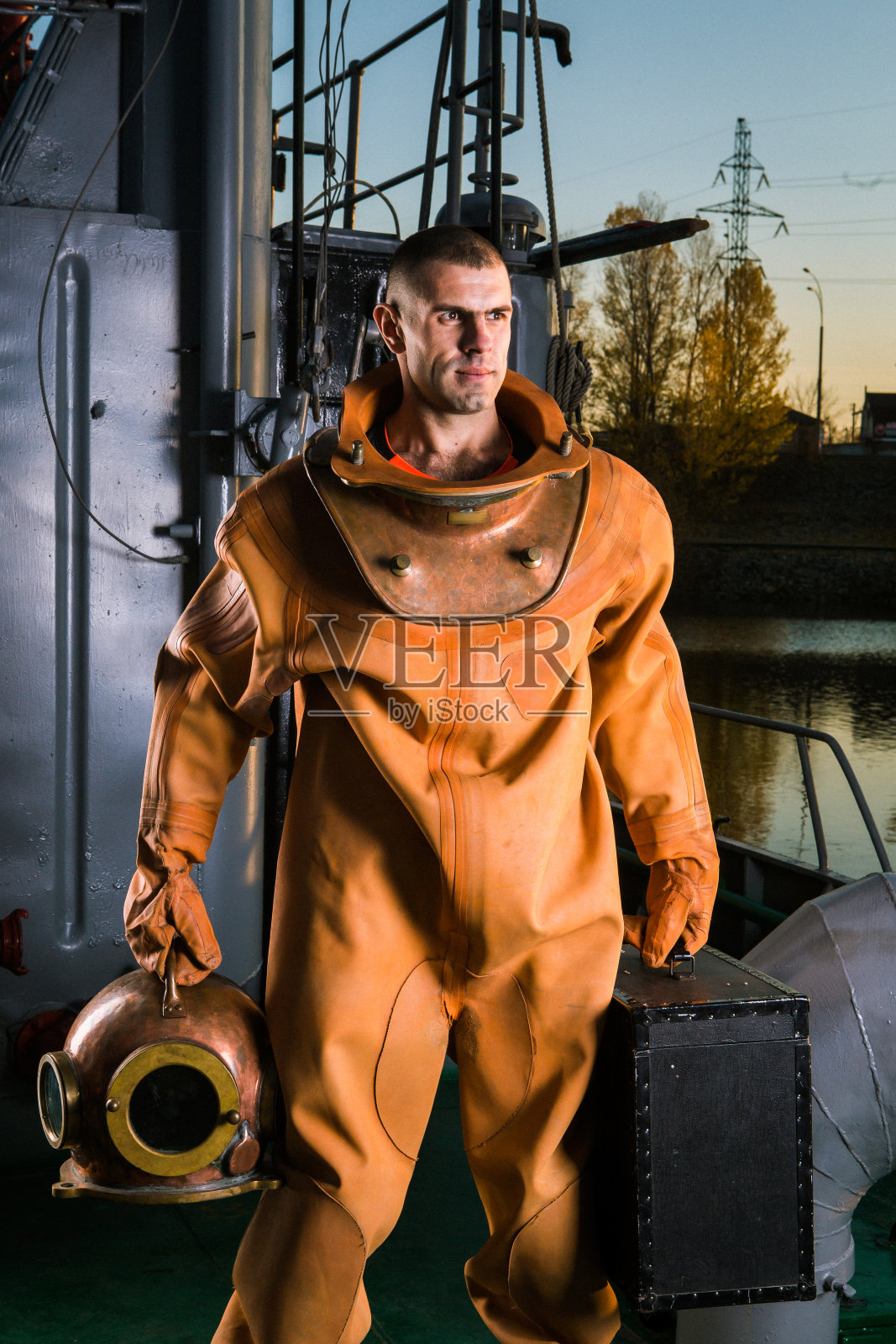 一个穿着复古潜水服的人正带着设备站在船上照片摄影图片