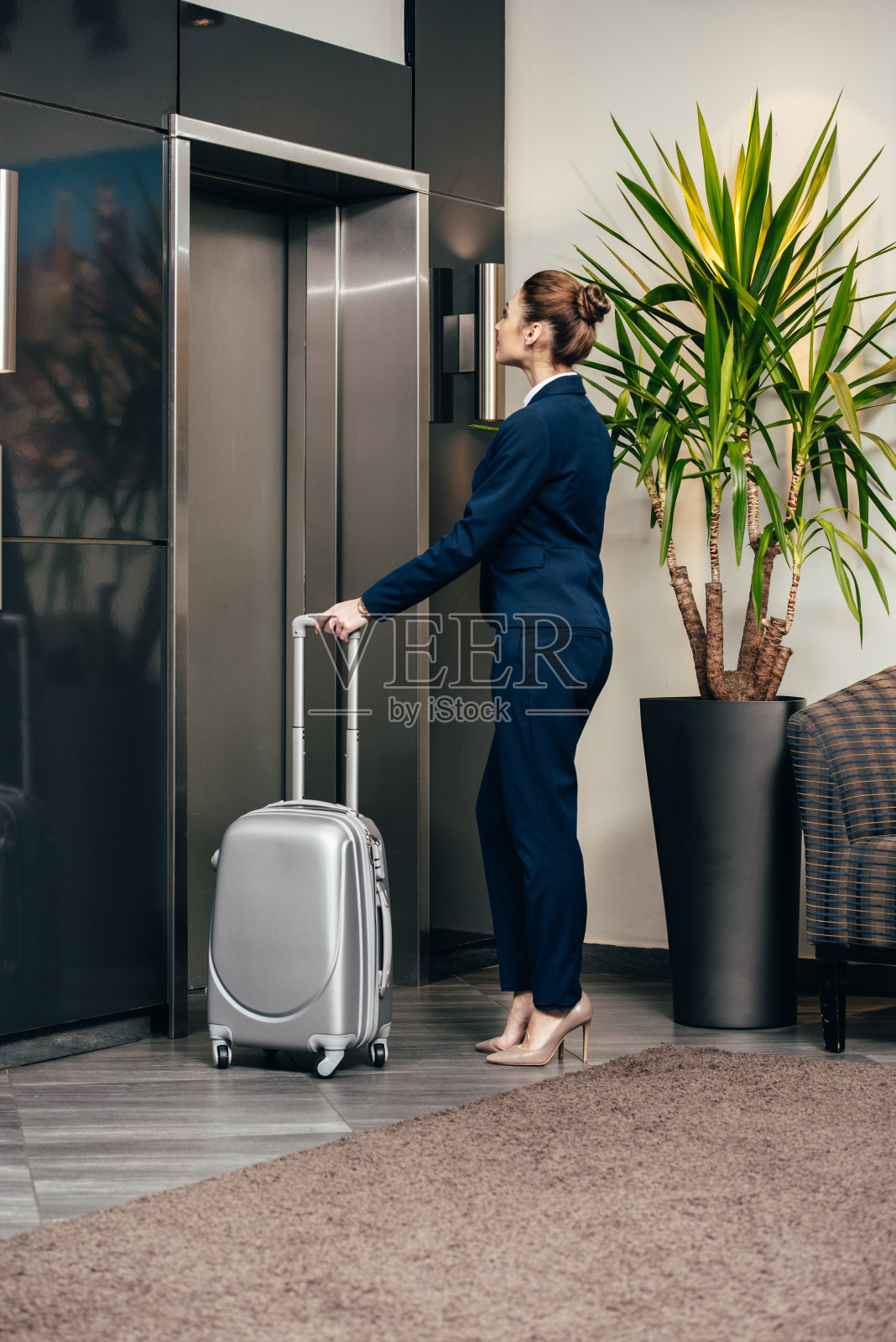年轻漂亮的女商人拿着行李在酒店等电梯照片摄影图片