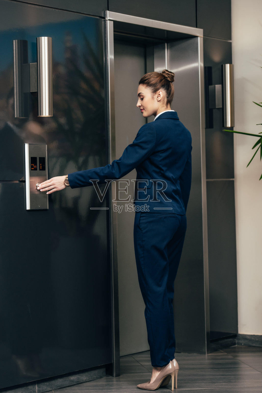 年轻迷人的女商人按电梯按钮照片摄影图片
