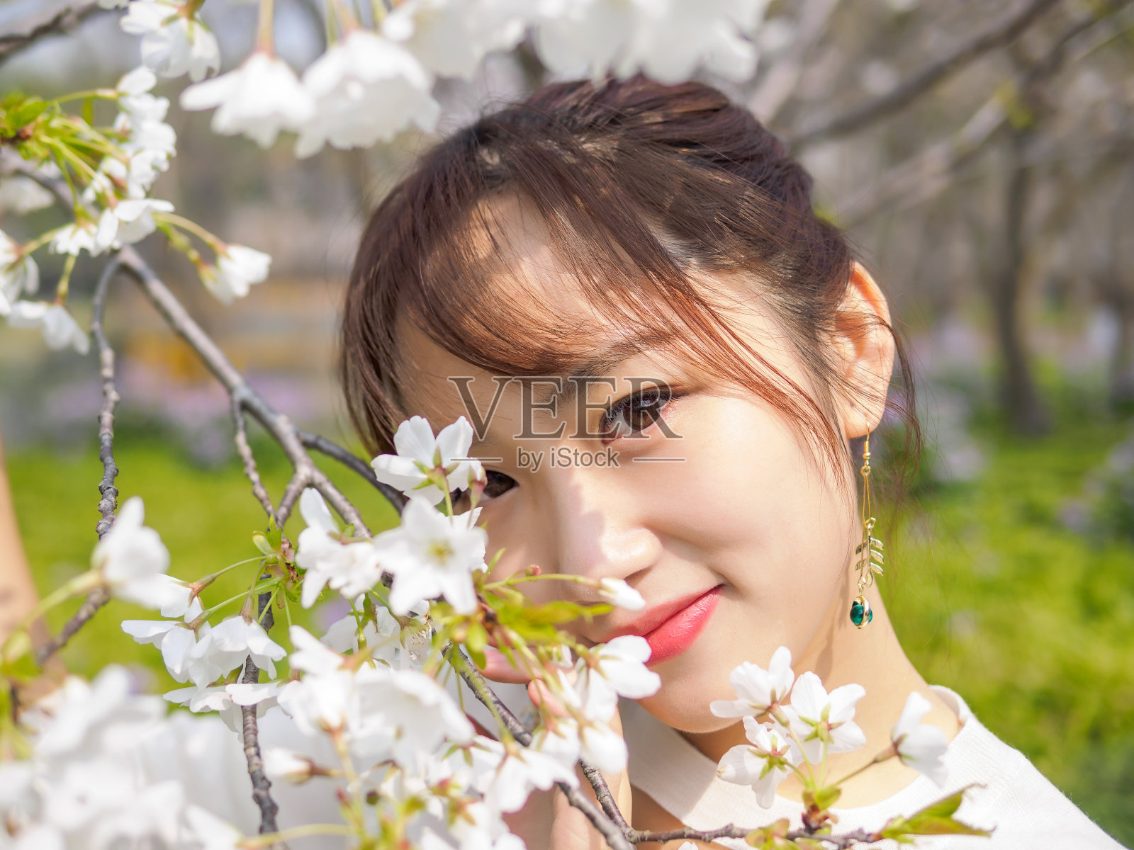 户外肖像美丽的年轻中国女孩微笑在盛开的樱花树早午餐在春天的花园，美丽，夏天，情感，表达和人们的概念。照片摄影图片