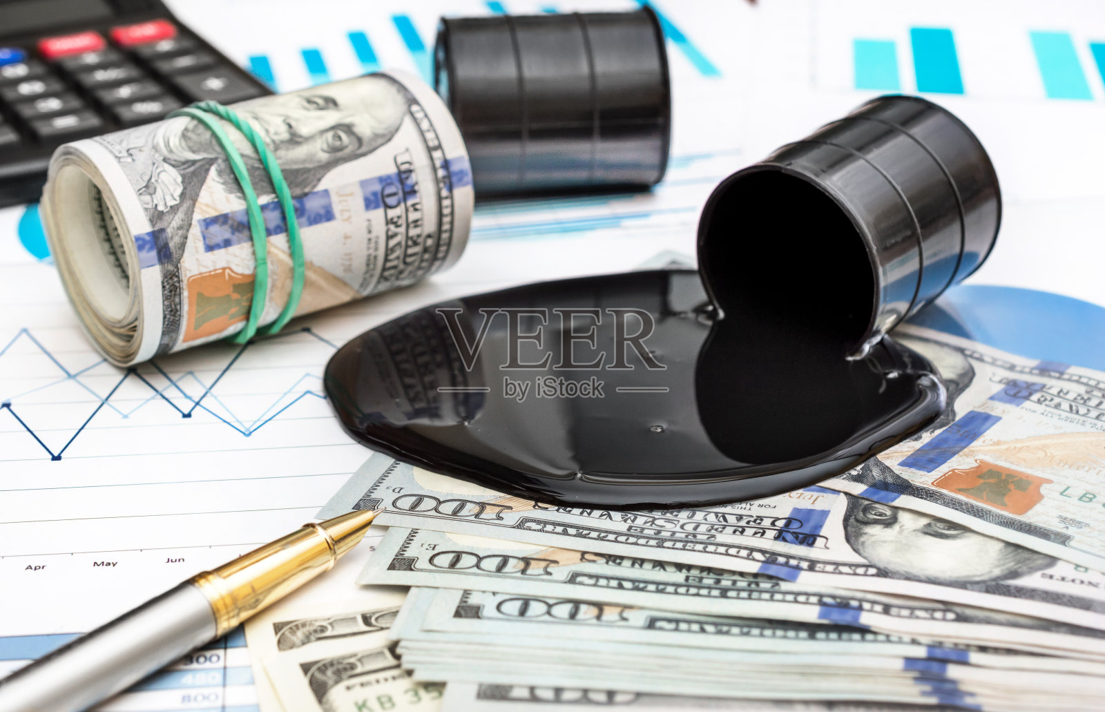 用金钱和计算器在金融图表上洒下原油。照片摄影图片