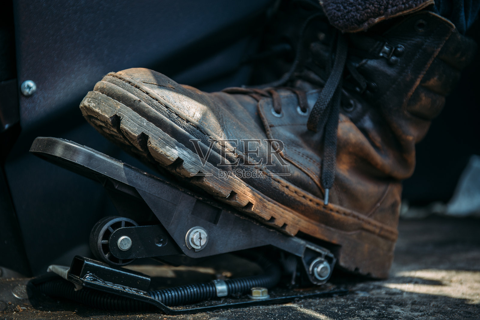 工人穿着大鞋或靴子踩着工业挖掘机或拖拉机的踏板照片摄影图片