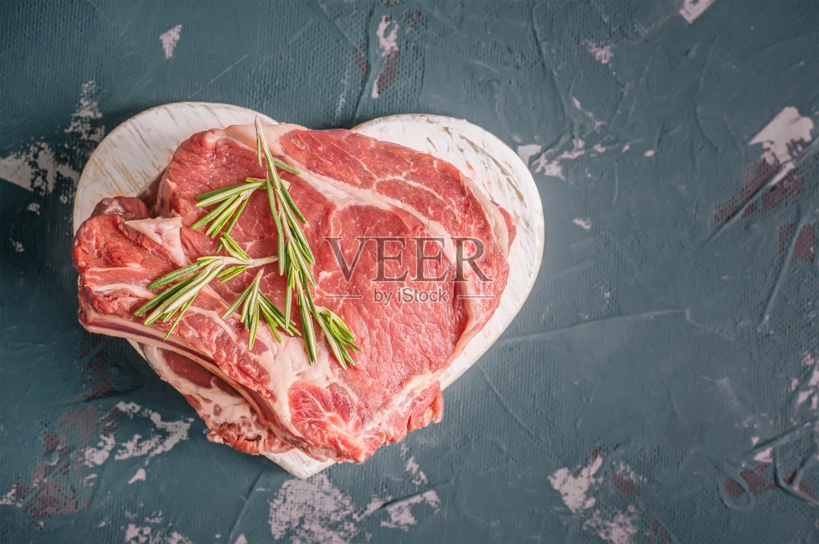把牛肉切在木板上烤，加上月桂叶，用迷迭香做腌料。副本的空间。照片摄影图片