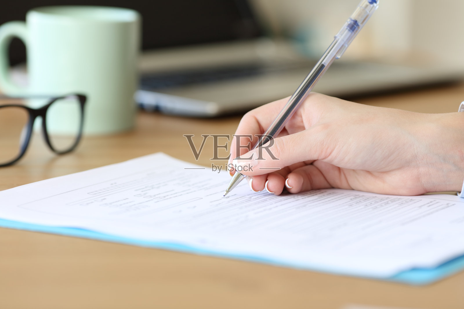 一个女人在桌子上填写表格的特写照片摄影图片