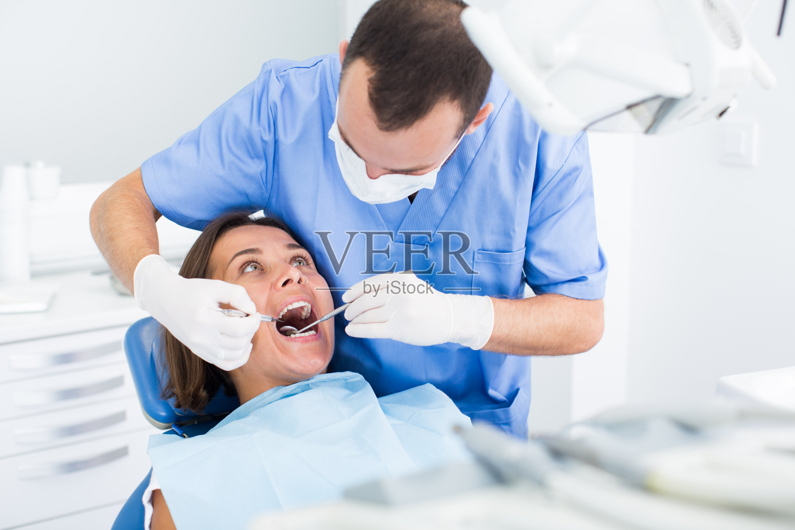 牙医正在治疗一位坐在牙科椅上的女性病人照片摄影图片