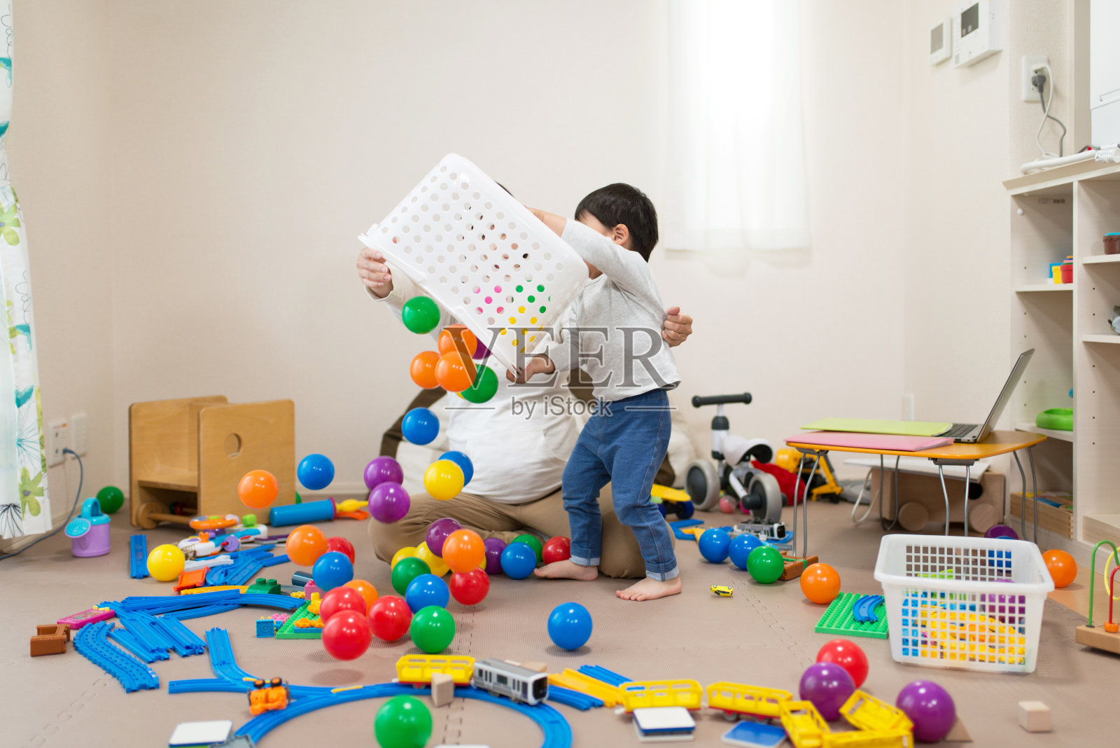 孕妇和蹒跚学步的孩子在不整洁的房间里玩玩具照片摄影图片