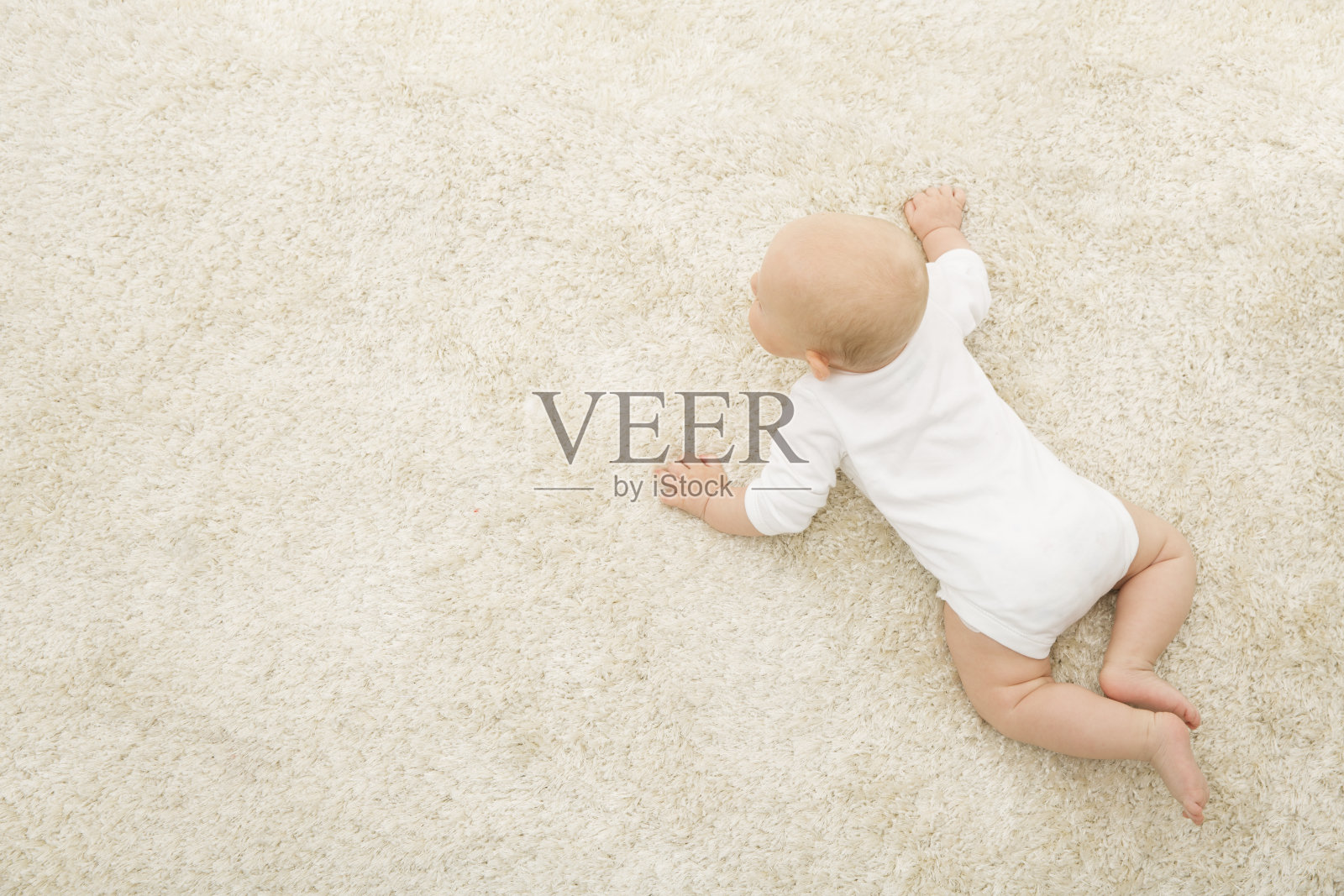 爬行婴儿在地毯背景，孩子俯视图，新生儿在米色毯子照片摄影图片