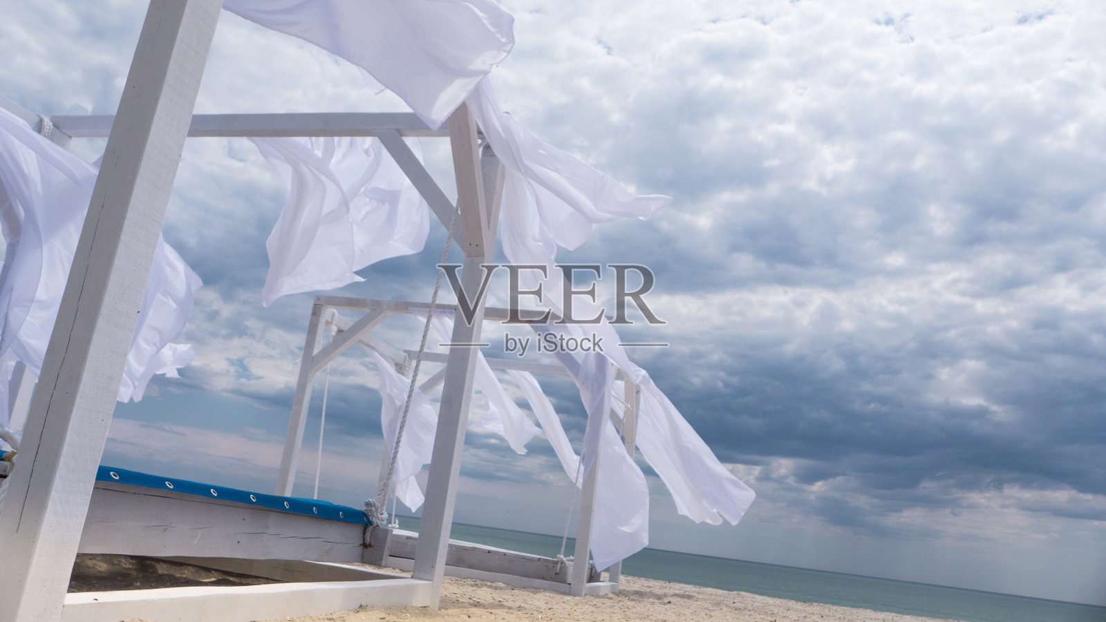 在海风的吹拂下，用白色的窗帘搭起遮阳篷照片摄影图片