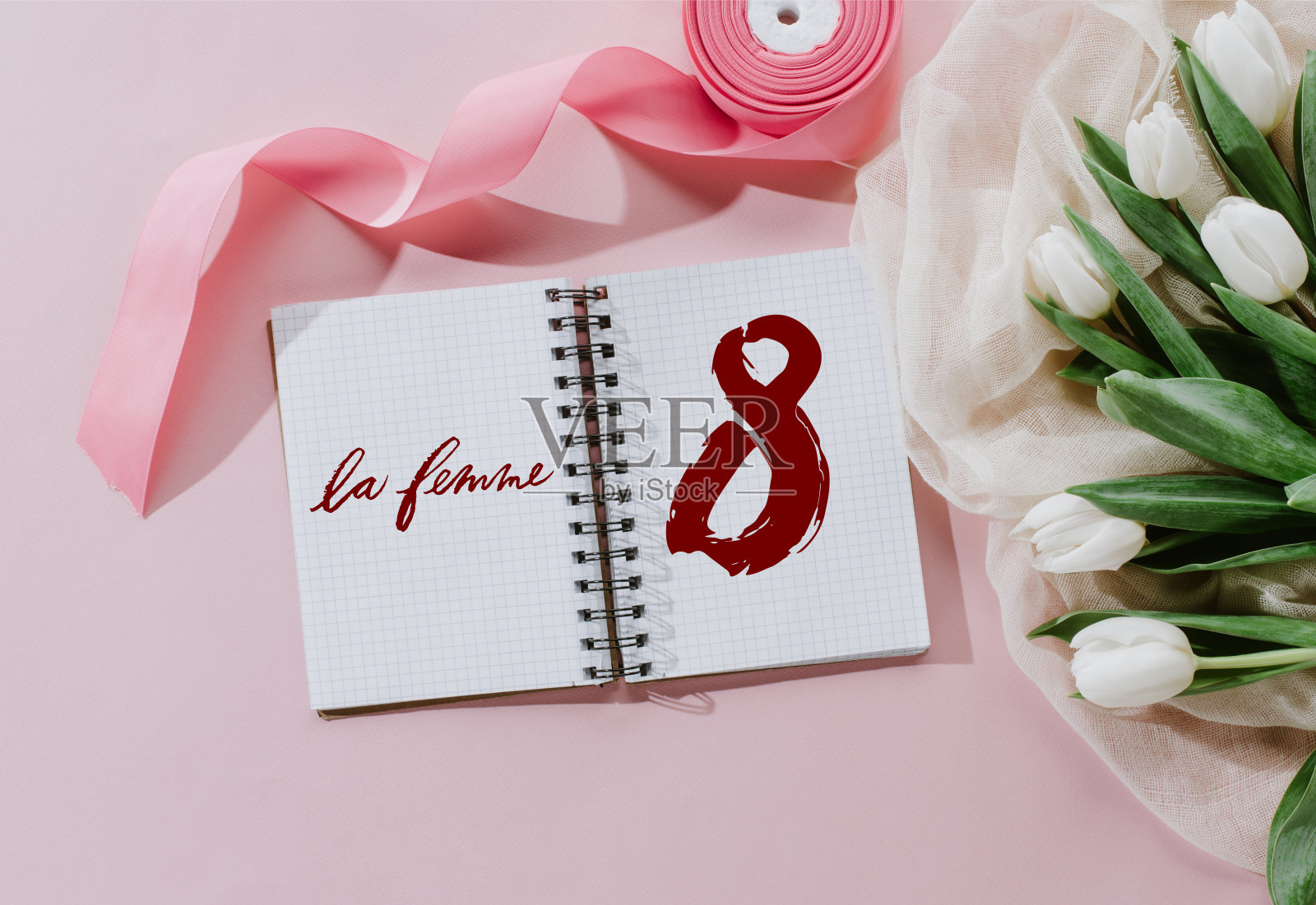 俯视图的LE FEMME标志在记事本，粉红丝带和白色郁金香为国际妇女节照片摄影图片