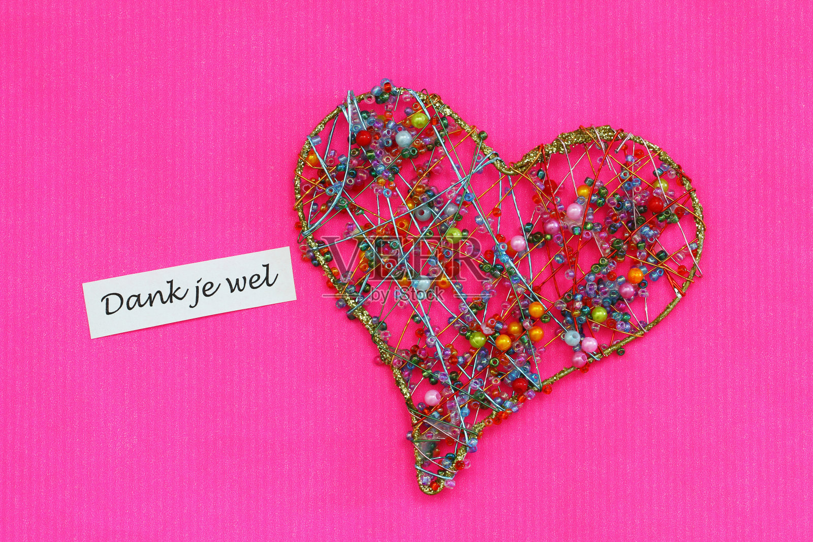 Dank je wel(谢谢你在荷兰语)卡片与心在鲜艳的粉红色表面照片摄影图片