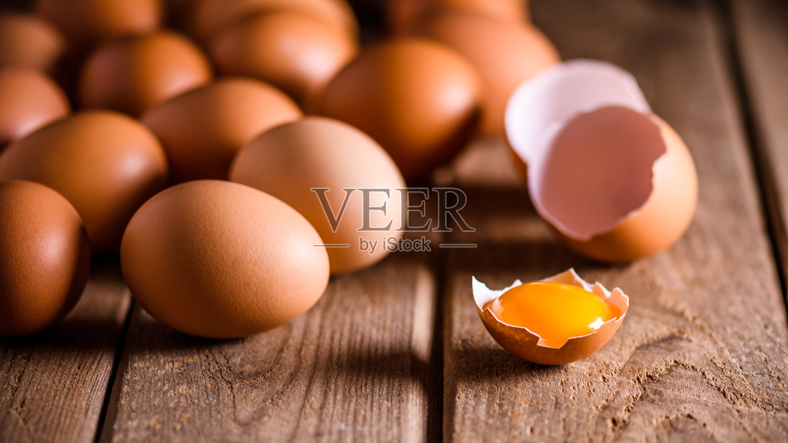 木桌上放着棕色的鸡蛋，鸡蛋碎了，眼睛上有蛋黄，还有文字空间照片摄影图片