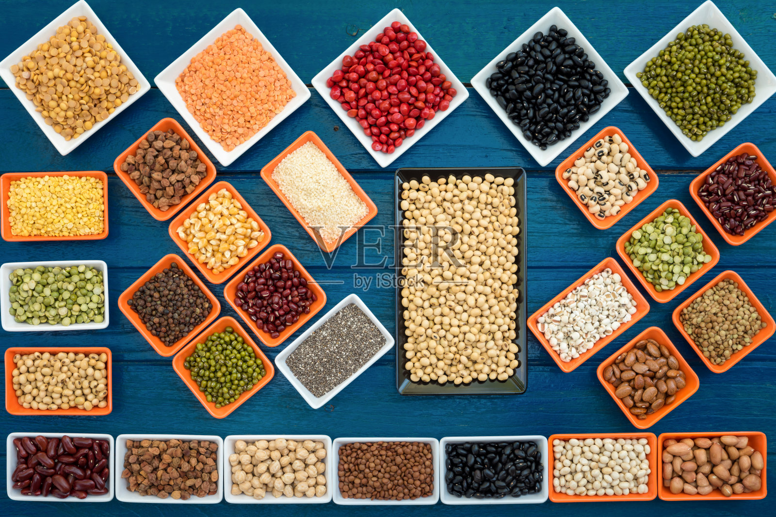 多色的干燥豆荚在容器的皮lay在蓝色板为背景，不同的干豆类吃健康，饮食和健康的生活方式，收集干燥豆荚有机烹饪照片摄影图片