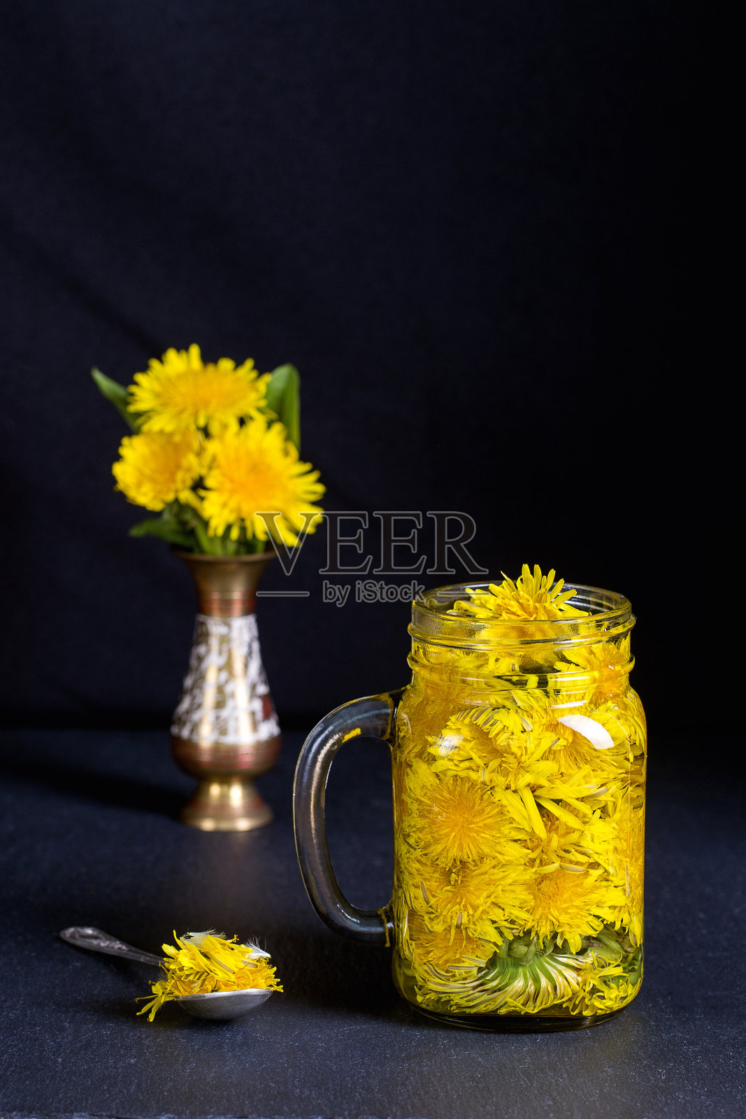 蒲公英黄花茶饮在玻璃杯上的黑色背景。健康饮食的概念照片摄影图片