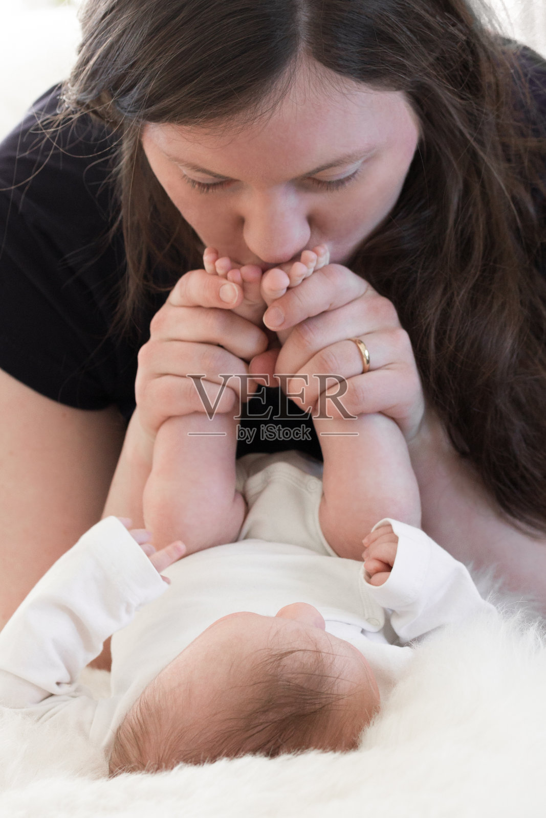 妈妈亲吻她的宝宝的脚，当他们玩和亲密照片摄影图片