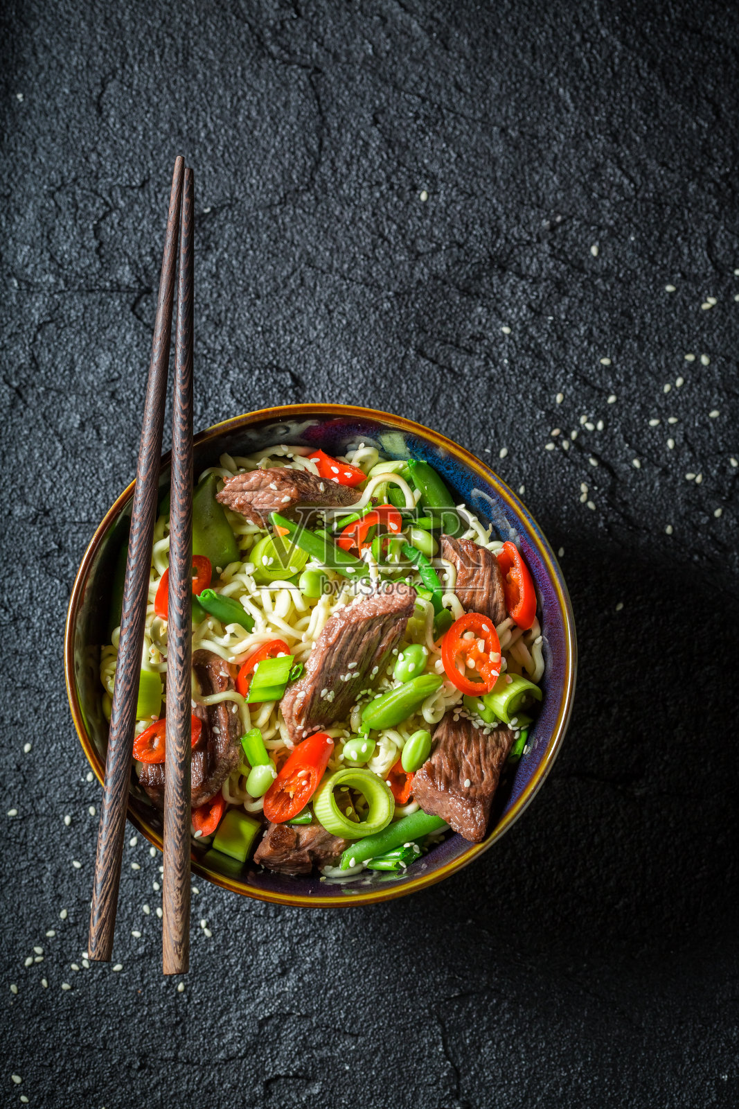 黑色餐桌上的亚洲辣面条，配牛肉和蔬菜照片摄影图片