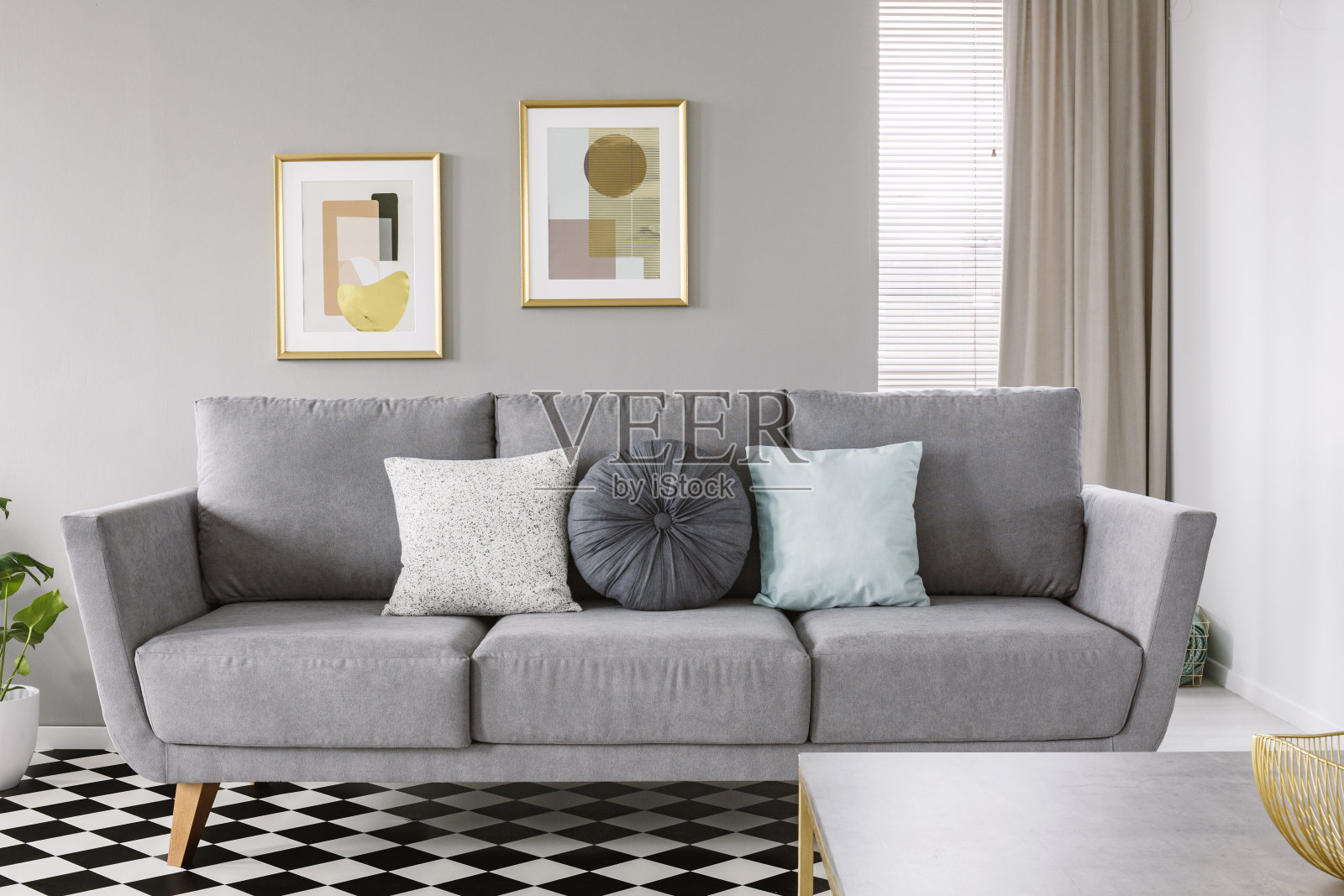 真实的照片，一个灰色的沙发，黑色和白色的枕头，在客厅内部，格子地板和海报在墙上的黄金框架照片摄影图片