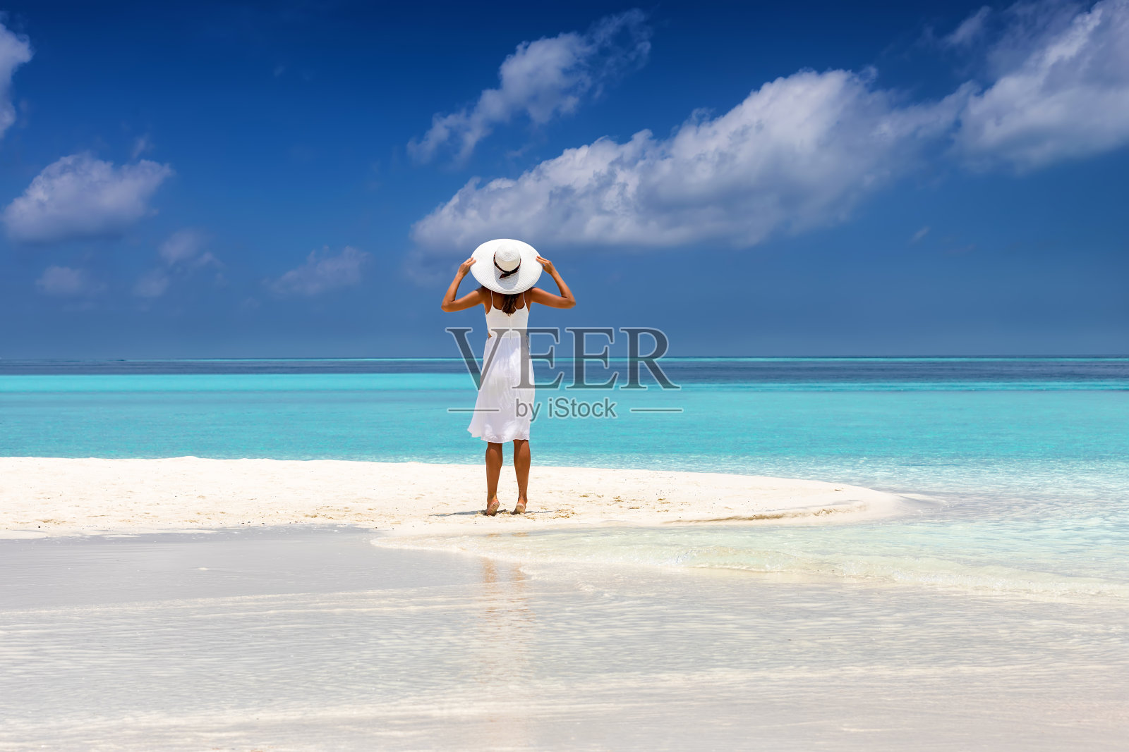 美丽的女人穿着白色的裙子站在热带的海滩上照片摄影图片