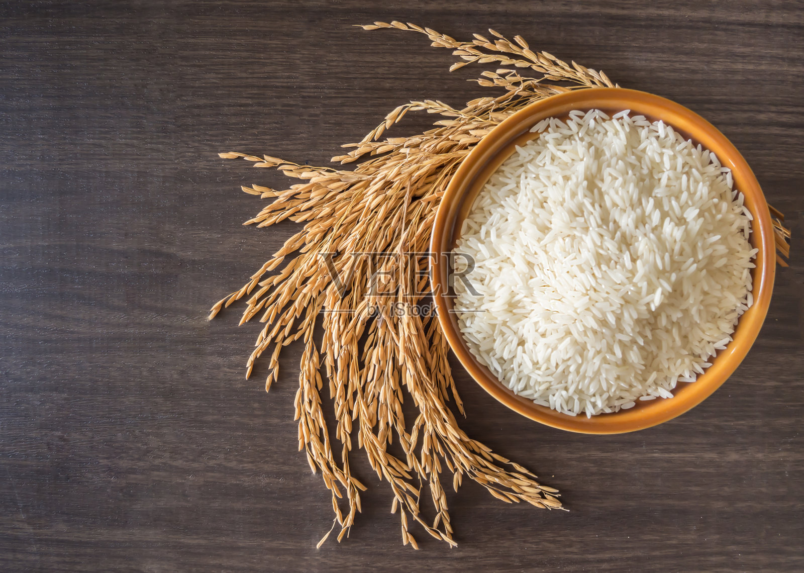 糙米(泰国茉莉花米)放在棕色的碗里，谷穗或未碾碎的米放在木头的背景上照片摄影图片