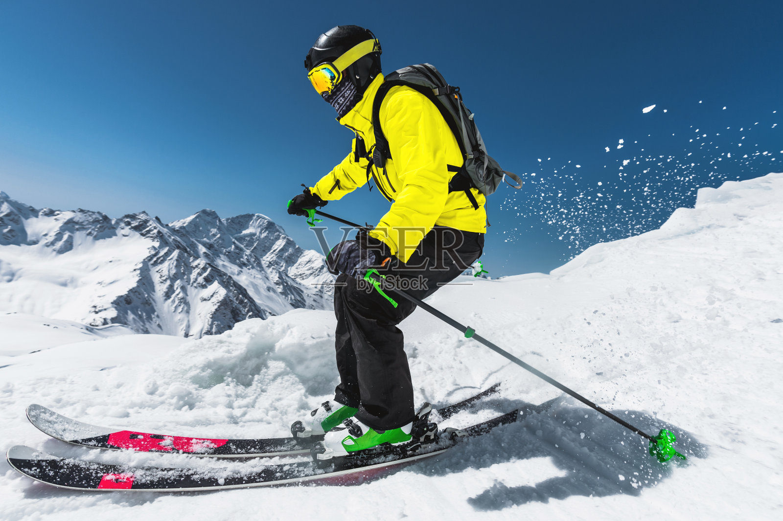 专业滑雪者在冬季从冰川上跳跃前的速度对着蓝天和高山照片摄影图片