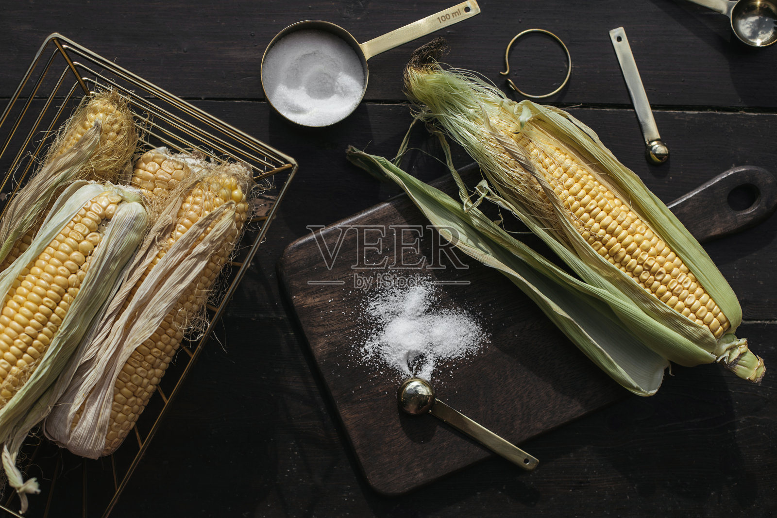 用切菜板和盐将成熟的玉米谷粒放在深色的木质背景上。夏季素食晚餐或零食。平放俯视图照片摄影图片