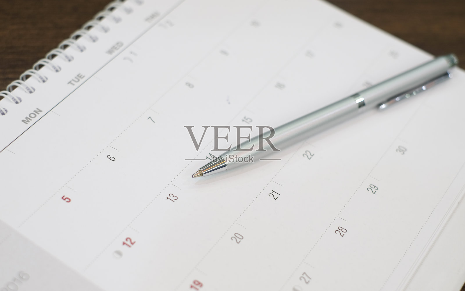 近距离用圆珠笔在日历上准备写日期约工作，会议:办公用品为企业概念照片摄影图片