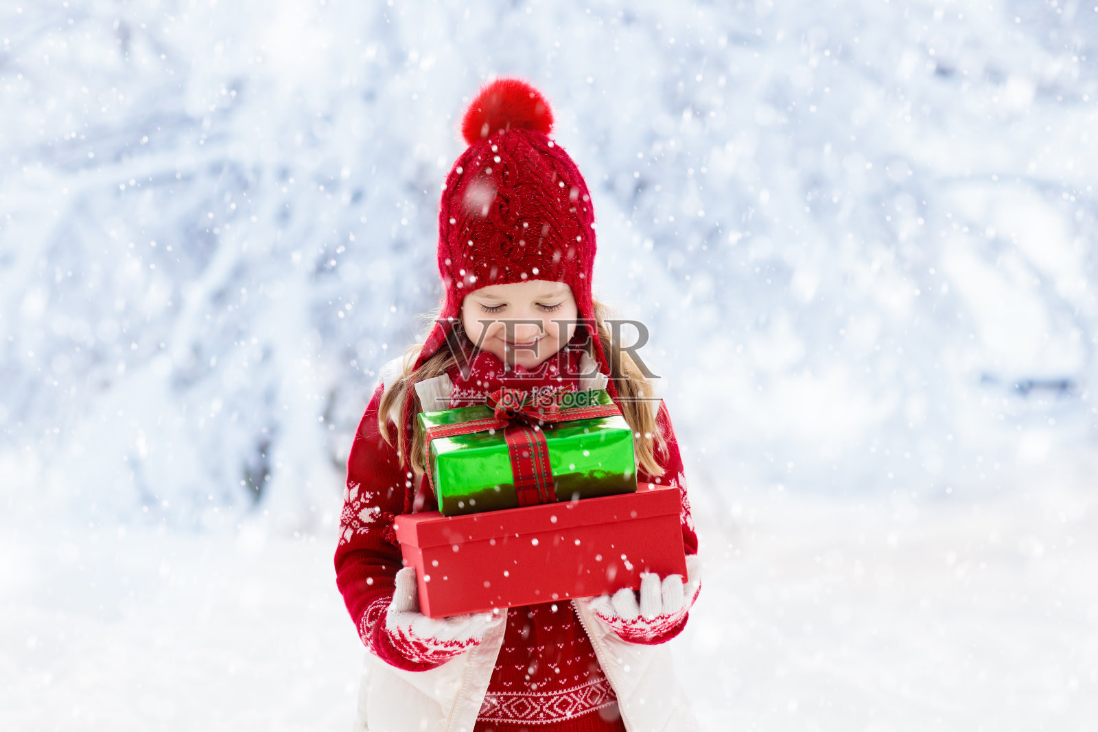 孩子在雪地里拿着圣诞礼物。孩子们的礼物照片摄影图片