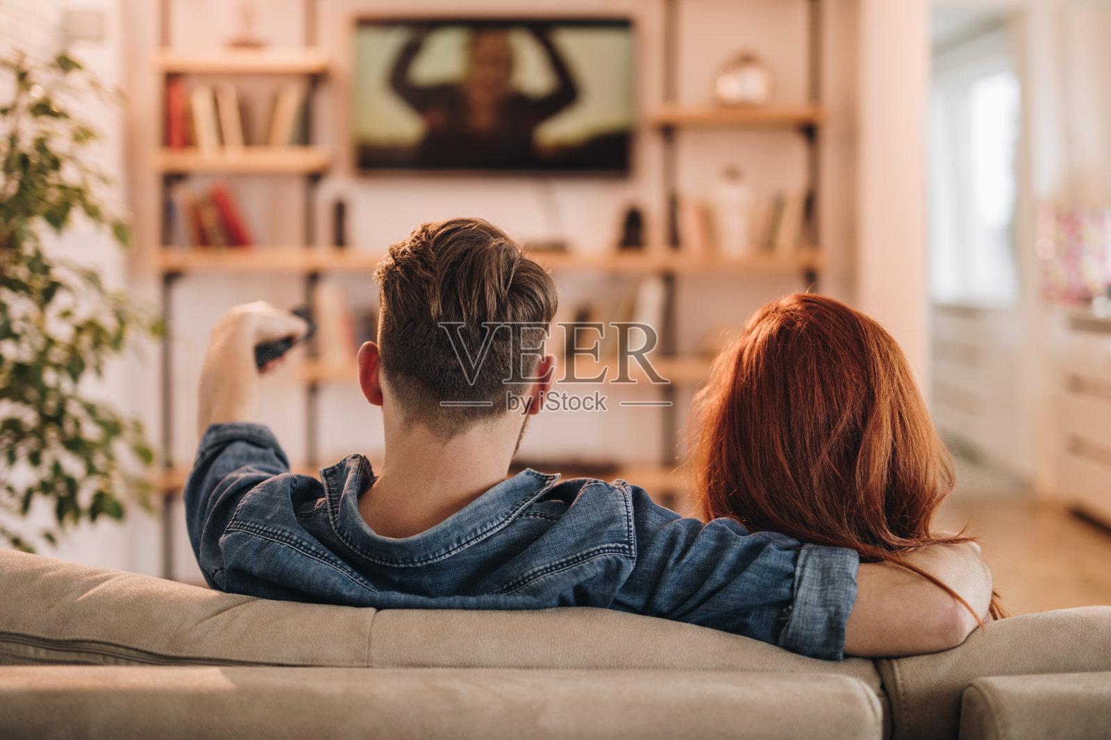 一对夫妇在家看电视的背影。照片摄影图片