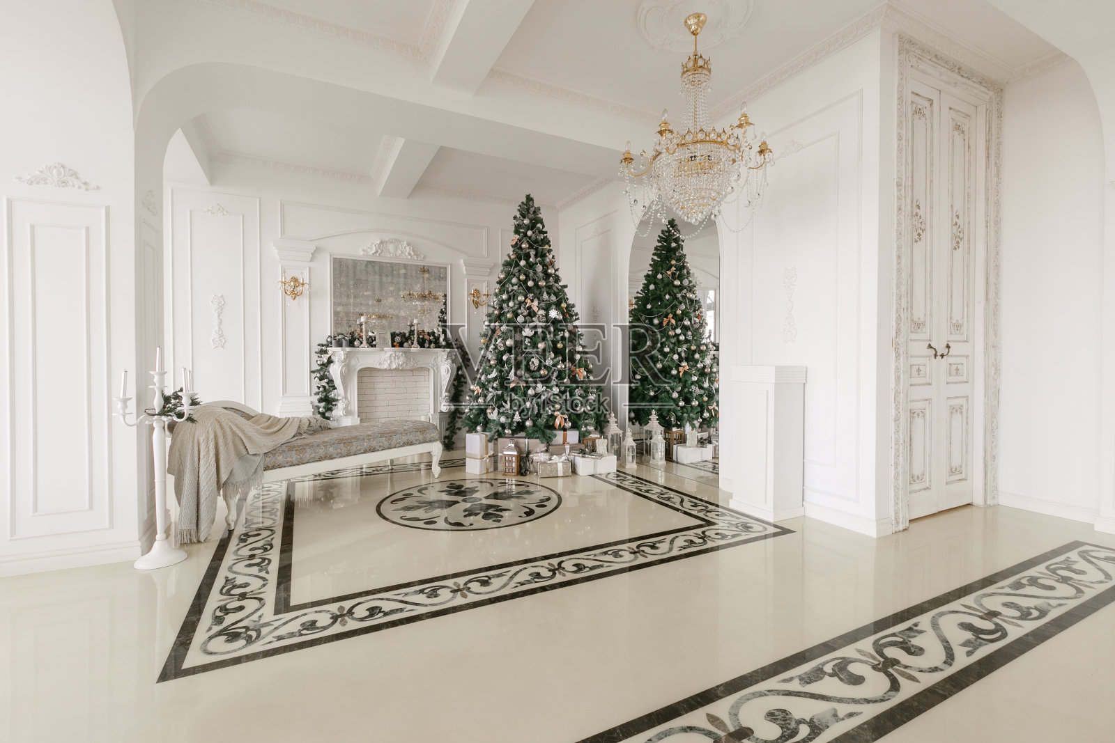 圣诞节的早晨。经典豪华公寓配有白色壁炉，装饰过的圣诞树，沙发，大窗户和吊灯。照片摄影图片