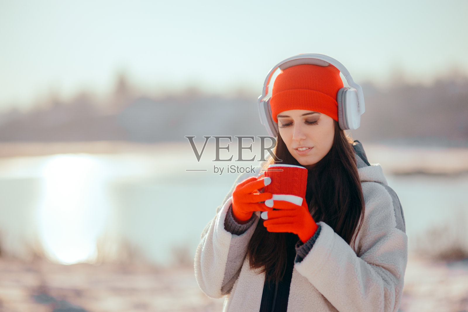 冬天的女人喝热饮料听音乐照片摄影图片