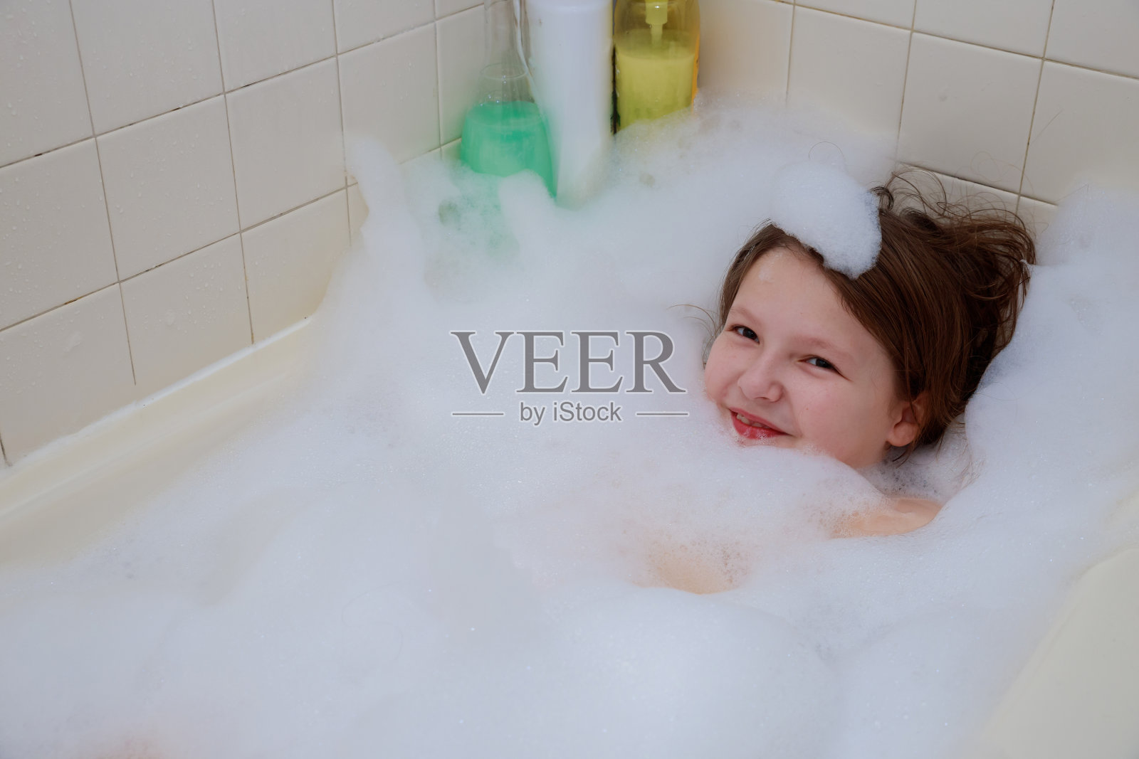 快乐的宝宝在沐浴，在泡沫淋浴中游泳。照片摄影图片