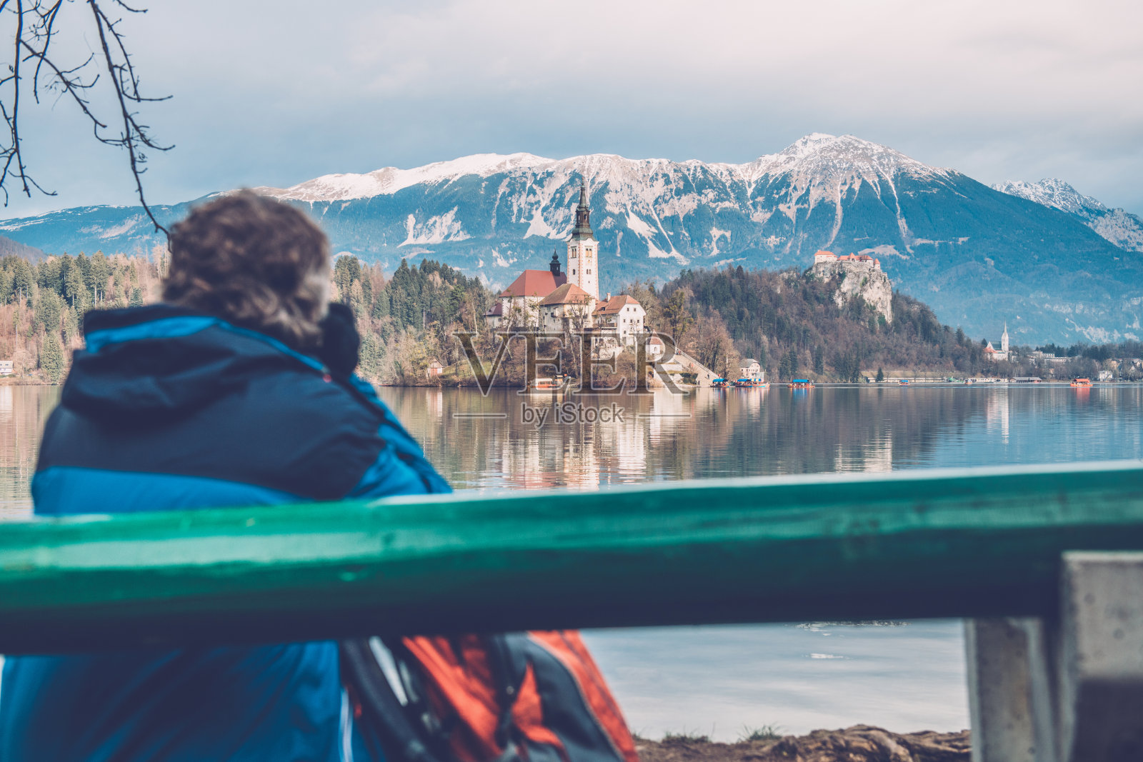 高级男子坐在长椅上欣赏在斯洛文尼亚，欧洲流血湖上的岛屿照片摄影图片