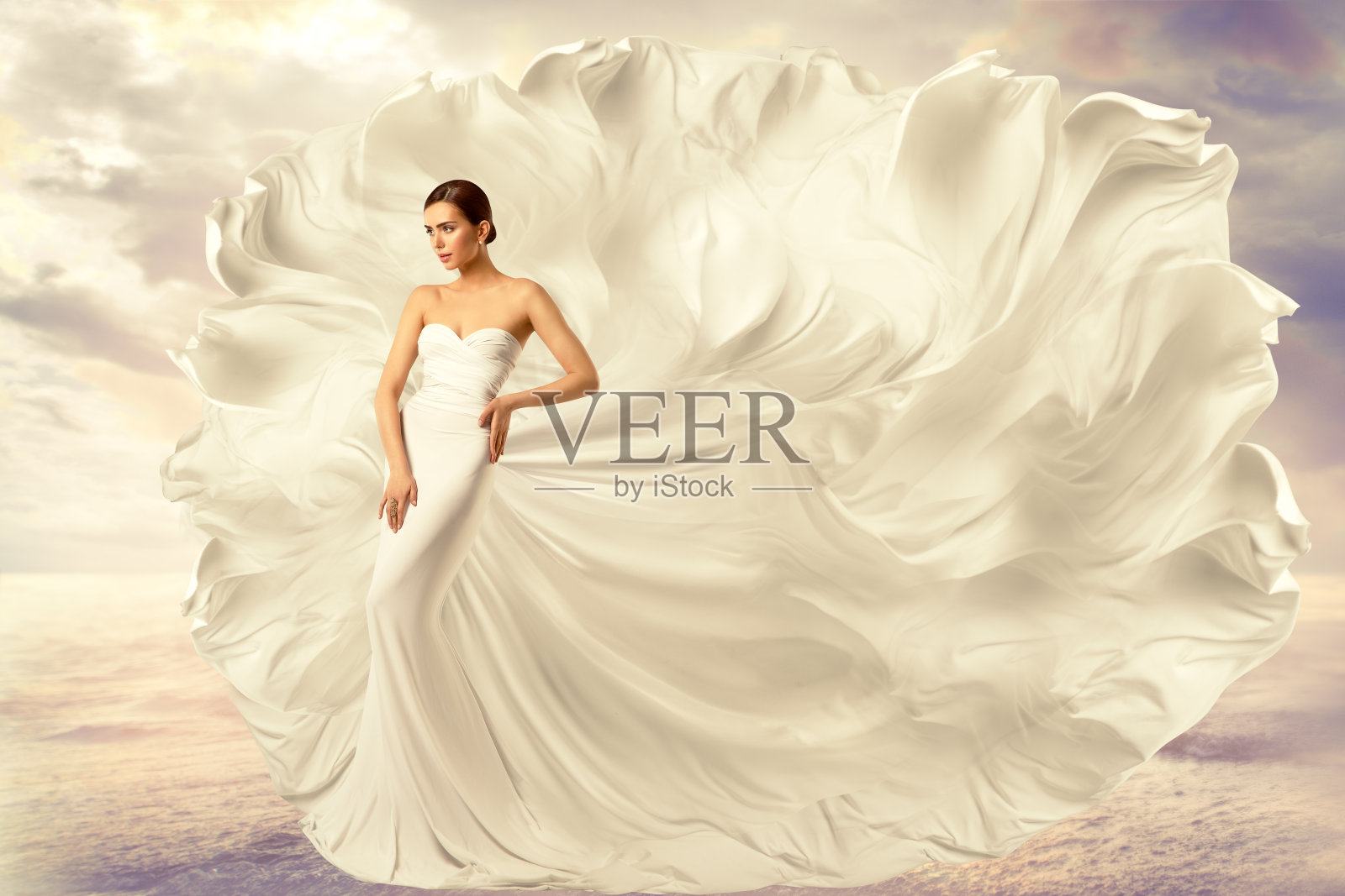 女人白色连衣裙，时尚模特在长丝绸摆动长袍，飞舞飞舞的织物在风照片摄影图片