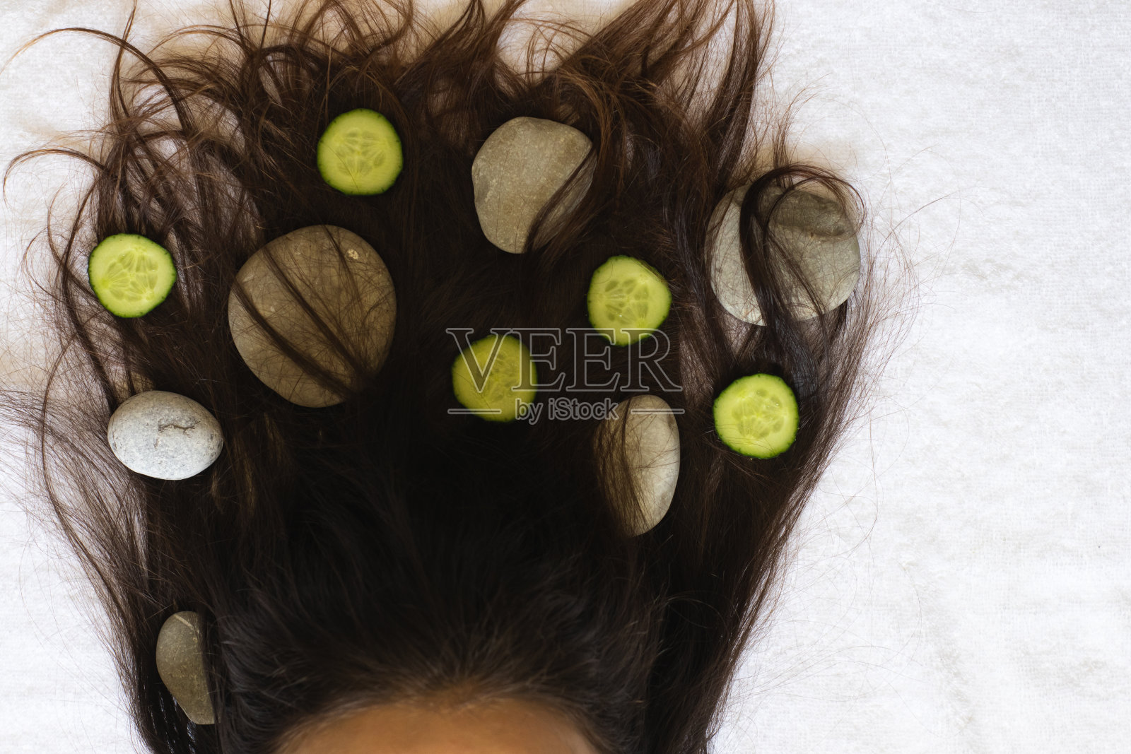 年轻女孩的头发上缠着温泉石和黄瓜照片摄影图片